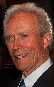 A headshot of an older man is looking to the left while smiling