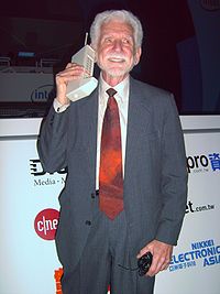 Мартин Купер в 2007 году. В руках одна из первых моделей сотового телефона.